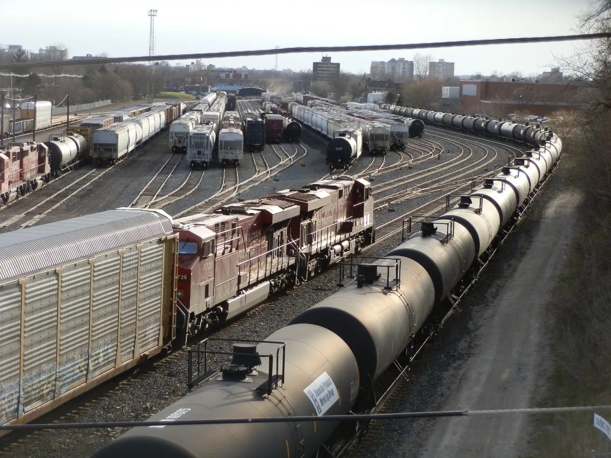 A massive merging of industrial trains in a train yard with blue and brown colors apparently in the morning.